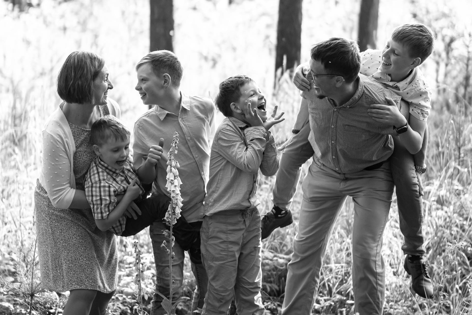 Rodina s dětmi zachycená v pohybu při venkovní hře, černobílá fotografie.